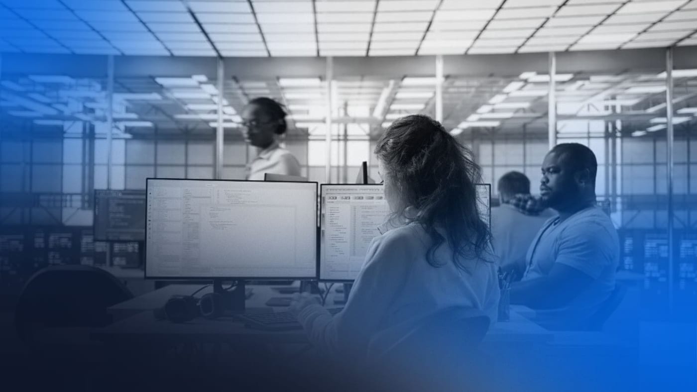 Profissionais trabalhando em estações com múltiplos monitores em ambiente tecnológico, ilustrando operações de empresas de desenvolvimento de software.