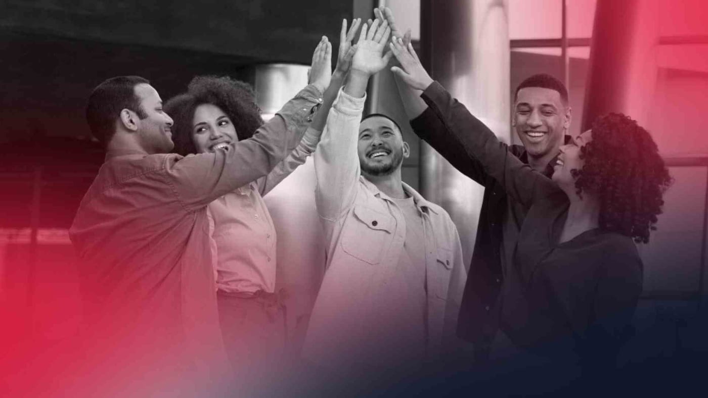 Grupo de profissionais celebrando o sucesso de um projeto com as mãos unidas, simbolizando integração de equipe e colaboração organizacional.