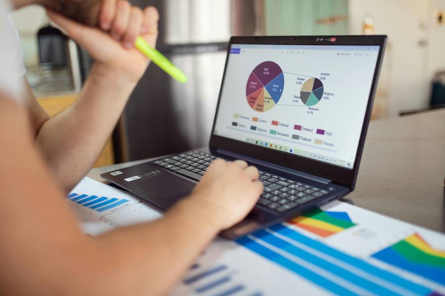 Mulher mexendo no computador, analisando gráficos de um produto de sucesso.