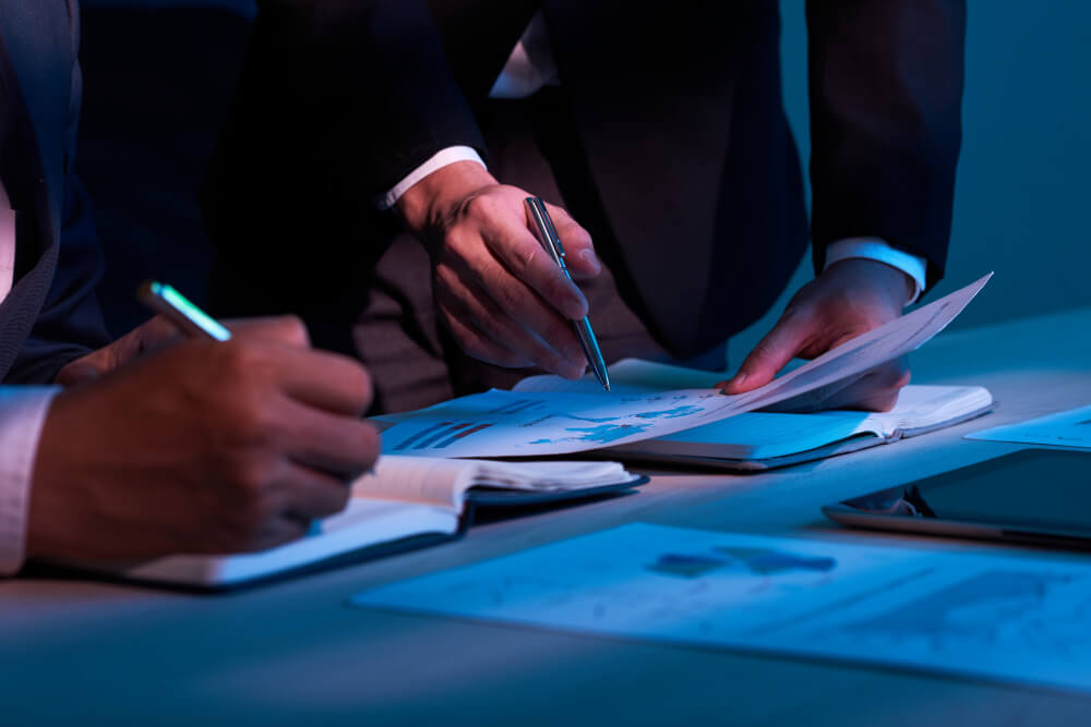 Executivos analisam documentos e gráficos financeiros, representando o impacto estratégico do Open Finance Brasil.