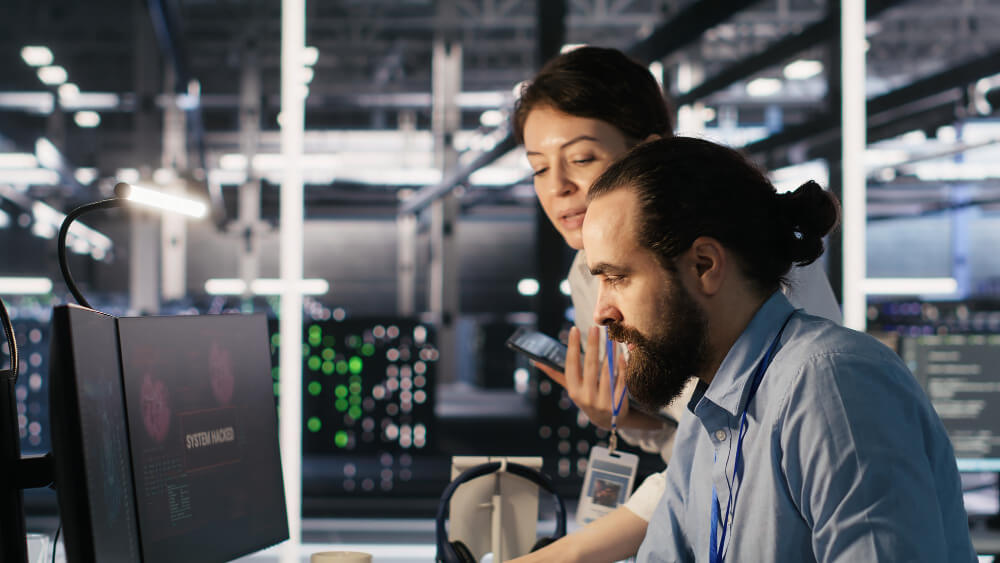 Profissionais de tecnologia analisando dados e sistemas em ambiente corporativo, representando uma empresa de outsourcing de TI em operação.