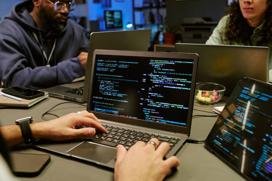 Desenvolvedor digitando código em laptop durante sessão de observabilidade e monitoramento de sistema com agentes de IA